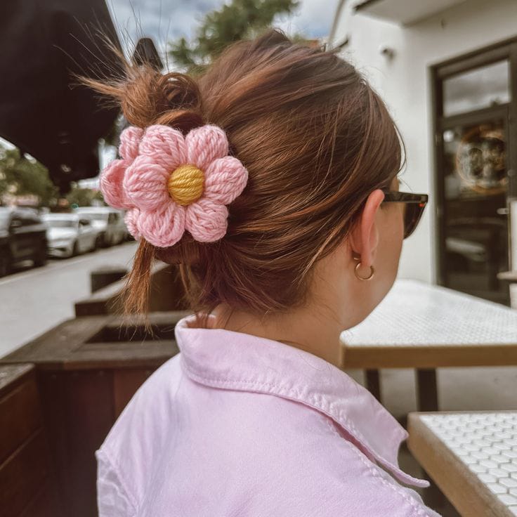 Handmade crochet pink daisy flower hair clip in bun hairstyle