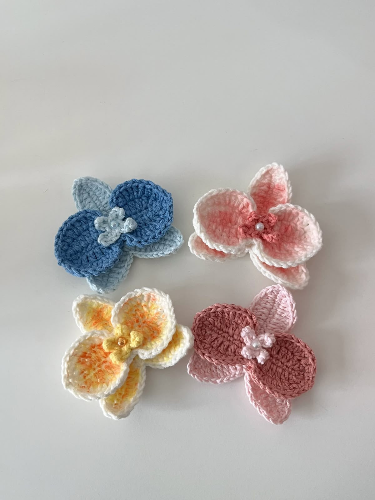 Handmade crochet butterfly hair clip in pastel pink and yellow with pearl bead hanging chains, aesthetic hair accessory for girls and women by Verity.