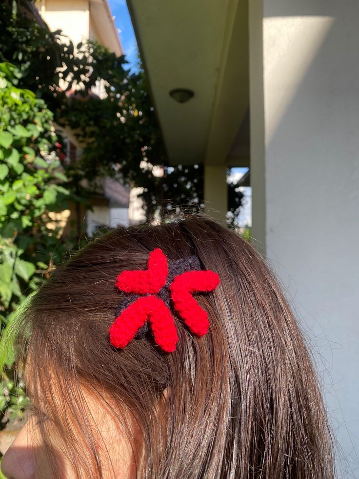 Handmade crochet red bow hair clip worn in brown hair.