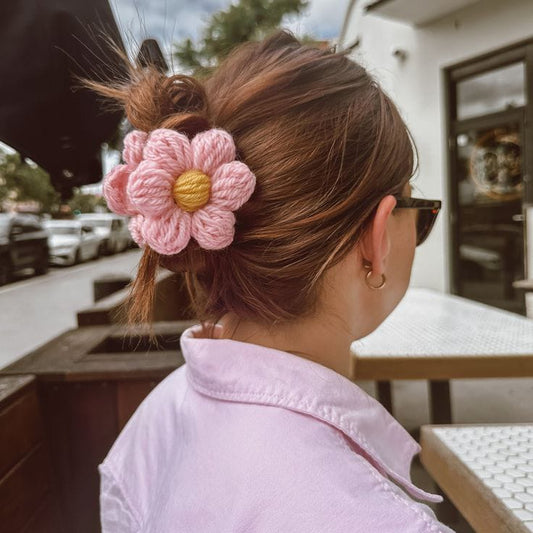 Handmade crochet pink daisy flower hair clip in bun hairstyle
